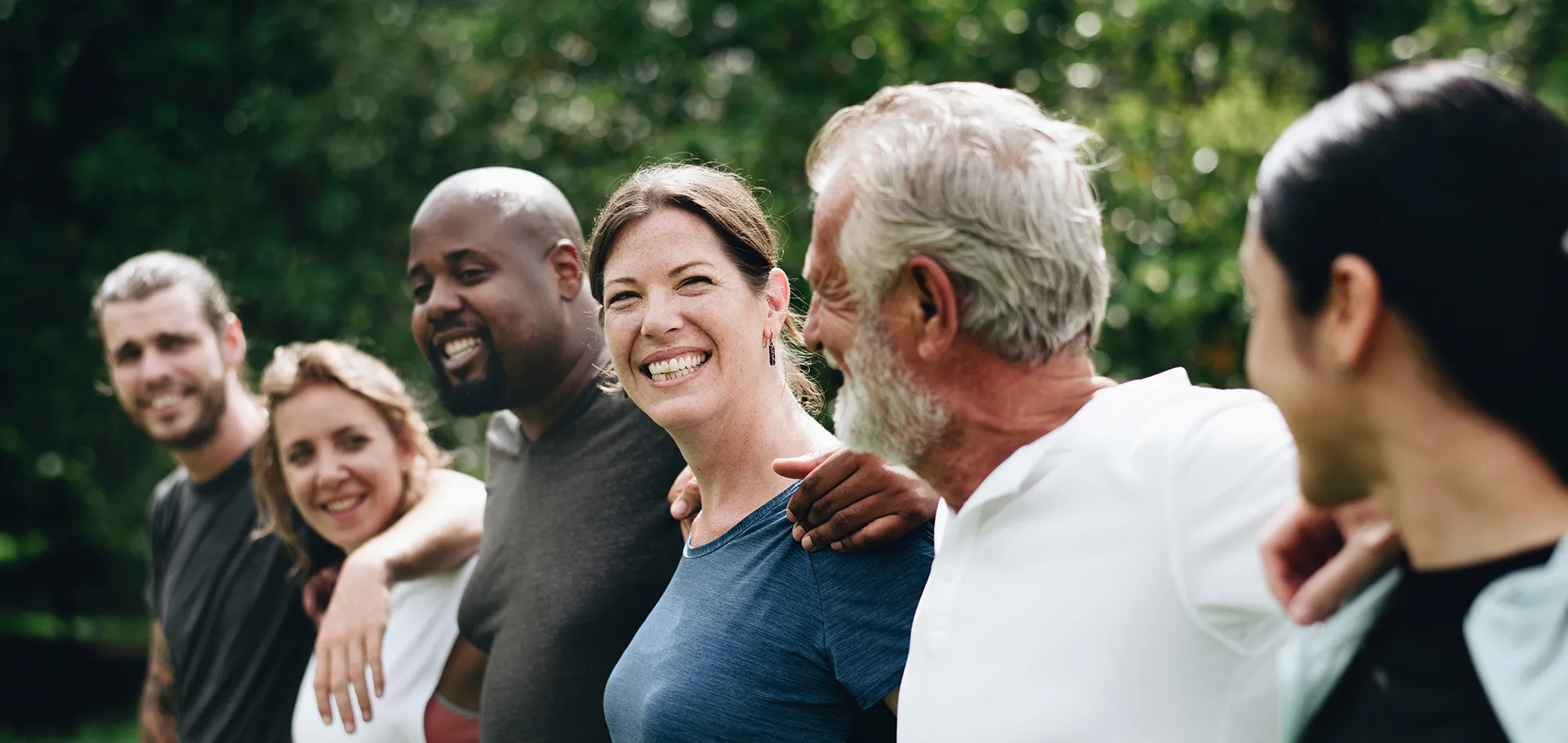 Groupe de marcheurs de tous âges, souriants et complices, dans un parc.