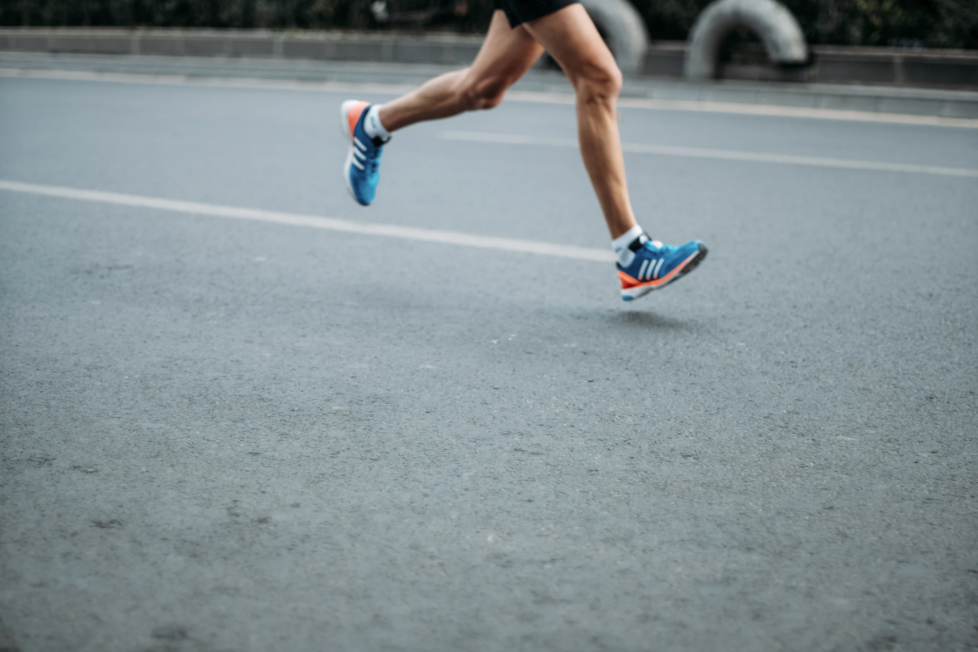 Cinquantaine de coureurs et coureuses devant une banderole d'arrivée, lumière dorée.